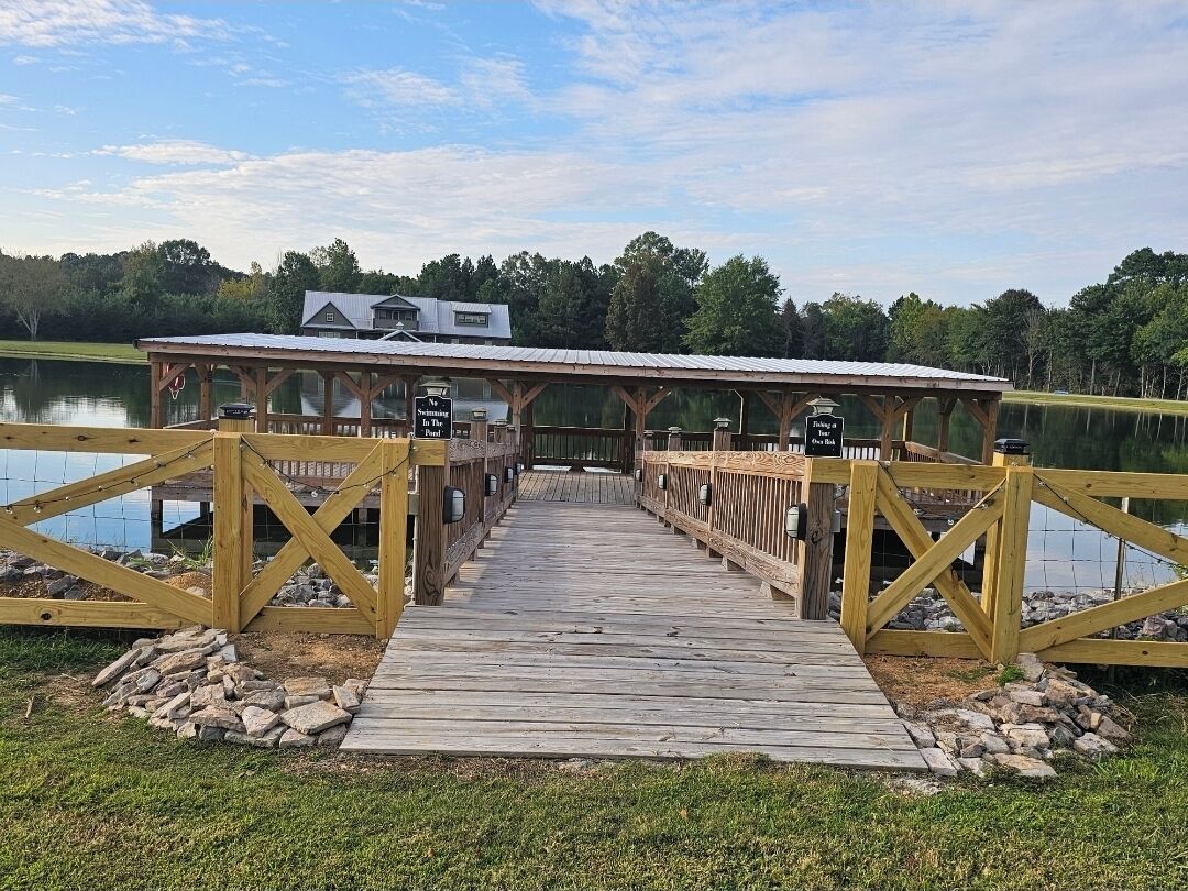 A wooden dock leading to a covered area with a sign indicating a fishing area.