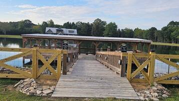 A wooden dock leading to a covered area with a sign indicating a fishing area.