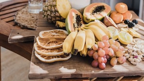 A wooden table with a variety of fruits and nuts, a glass of water, and pampas grass in the background. - Studio 22: Garden Serenity & Coastal Calm (Port Lincoln)