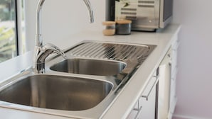 A modern kitchen with a stainless steel sink, a white countertop, and a built-in oven. - Studio 22: Garden Serenity & Coastal Calm (Port Lincoln)