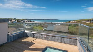 A rooftop terrace with a glass balustrade, wooden flooring, and a view of the sea and distant hills. - Seaesta Cottage, Holiday Cottage Broad Haven, Sleeps 8, 4 bedrooms,  bathrooms (Haverfordwest)