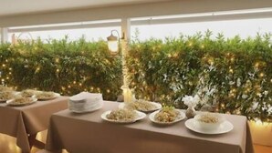 A restaurant with tables set for dining, a decorative wall with greenery, and a string of lights. - Windy's Leisure Villa  (Negombo)