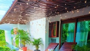 A covered outdoor seating area with wooden loungers, potted plants, and a ceiling with string lights. - Windy's Leisure Villa  (Negombo)