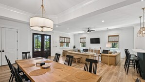Un'ampia zona giorno con un tavolo da pranzo in legno, sedie nere, un divano e una TV.