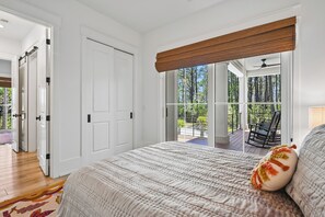 A bedroom with a large bed, a view of a balcony, and a door leading to another room. - New to VRBO, Steps to Beach, Pool, 5BR, Great Location (Hilton Head Island)