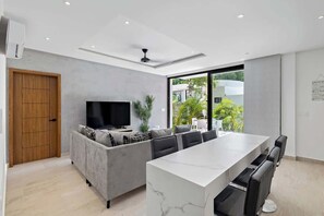 Een moderne woonkamer met een bank, televisie en eethoek.