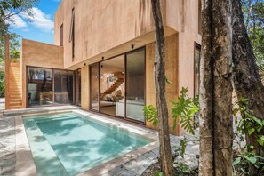 A modern house with a swimming pool, large glass doors, and a staircase leading to an upper level. - Designer stylish home with pool, near cenote. (Playa del Carmen)