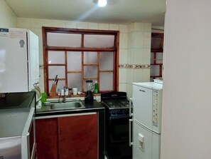 A compact kitchen with a refrigerator, stove, oven, and a window with blinds. - Bright 3BR in Central Cajicá. Walk to Plaza. Near Zipaquirá & Tabio (Cajicá)
