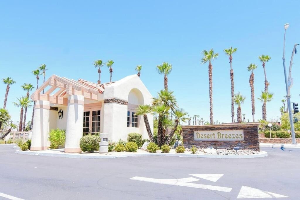 A building with a sign reading 'Desert Breezes,' surrounded by palm trees.