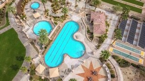 An aerial view of a resort with multiple swimming pools, a star-shaped sun patio, and a parking area. - 2-bedroom condo in serene Palm Desert with cool AC (Palm Desert)