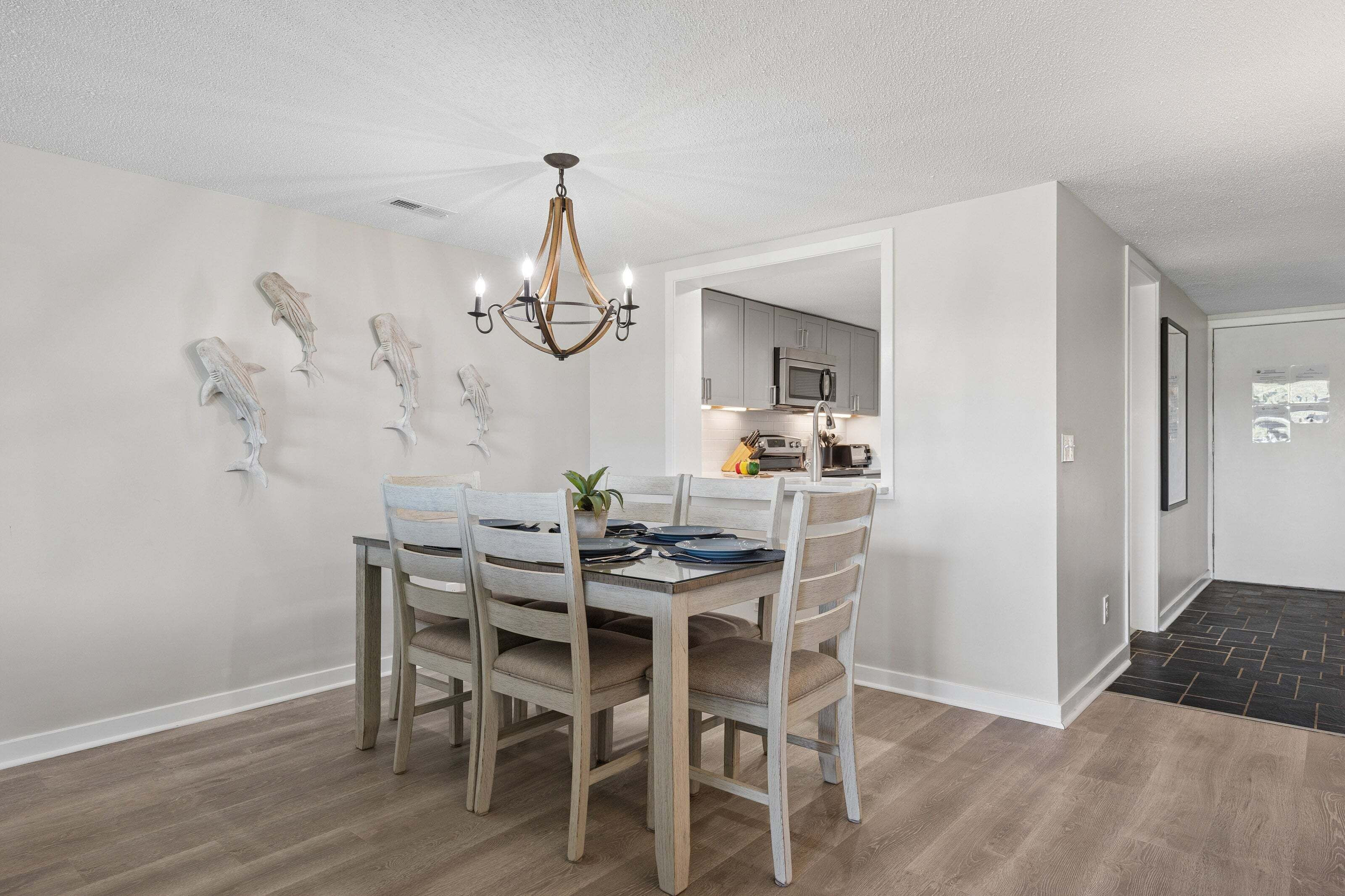 A dining area with a chandelier, wooden chairs, a table, and wall-mounted fish sculptures.