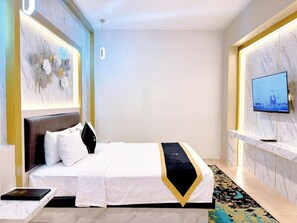 A hotel room with a bed, a TV, a desk, and a wall-mounted artwork. - Grand Malioboro Hotel Yogyakarta (Yogyakarta)