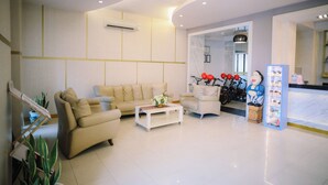 A modern living room with a beige sofa, a white coffee table, and a decorative statue. - Grand Malioboro Hotel Yogyakarta (Yogyakarta)