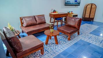 A living room with a sofa set, a coffee table, and a TV mounted on the wall.