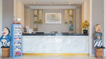 A reception desk with a marble counter, a framed logo, and decorative items including a statue and a shelf with bottles.