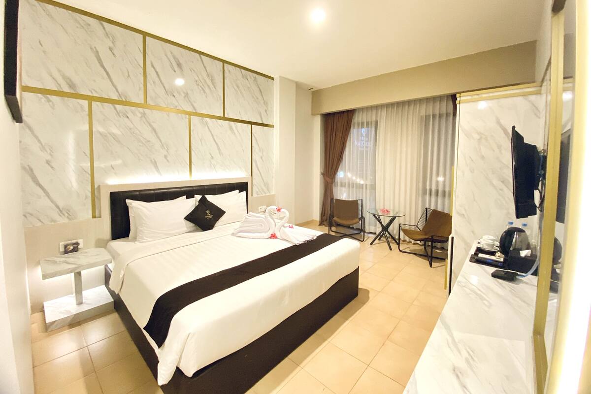 Ein Hotelzimmer mit einem großen Bett, einem Nachttisch, einer Sitzecke mit Stühlen, einem Tisch und einem Spiegel.