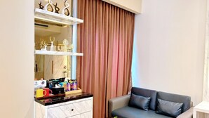 A modern living room with a sofa, a small coffee table, and a marble cabinet with decorative items. - Grand Malioboro Hotel Yogyakarta (Yogyakarta)