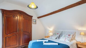 Un dormitorio con un armario de madera grande, una cama con ropa de cama floral y dos lámparas de noche.