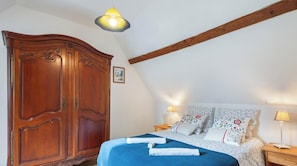 Una camera da letto con un'ampia armadiatura in legno, un letto con biancheria da letto floreale e due lampade da comodino.