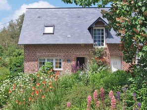 Una casa a due piani in mattoni con tetto spiovente, una piccola finestra al piano superiore e un ingresso al piano inferiore.