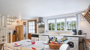 Una cocina con comedor, lavadora y escalera.