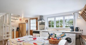 Una cucina con zona pranzo, lavatrice e scala.