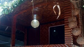 Een rustieke houten constructie met een wand in een herringbone patroon, een hanglamp en een deur.