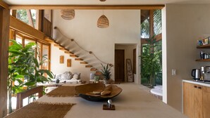 A modern interior with a staircase, wooden beams, and a kitchen area. - Bali Style Villa- Ocean view, AC,  Salt water pool, amazing kitchen! (Santa Teresa)