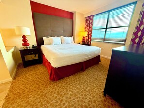 A hotel room with a large bed, two bedside tables, a desk, and a window with blinds. - 2-bedroom condo in terrific Las Vegas with AC and fitness room (Las Vegas)