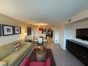 A living room with a sofa, a coffee table, a TV, and a kitchen in the background. - 2-bedroom condo in terrific Las Vegas with AC and fitness room (Las Vegas)
