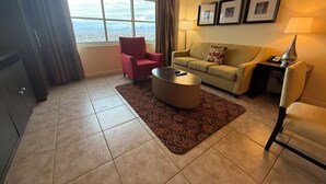 Ein Wohnzimmer mit einer Couch, Sesseln, einem Couchtisch und Blick auf die Stadt durch große Fenster.