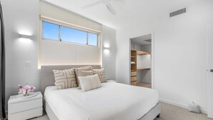 Une chambre à coucher avec un lit, une table de chevet, une commode et une fenêtre.