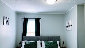 A bedroom with a bed, two nightstands, a window with curtains, and a ceiling light. - Indy-Themed Classic: Ode to Hoosier Spirit (Indianapolis)