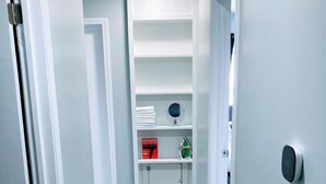 A hallway with white walls, a wooden floor, and a shelf with a mirror and a box. - Indy-Themed Classic: Ode to Hoosier Spirit (Indianapolis)