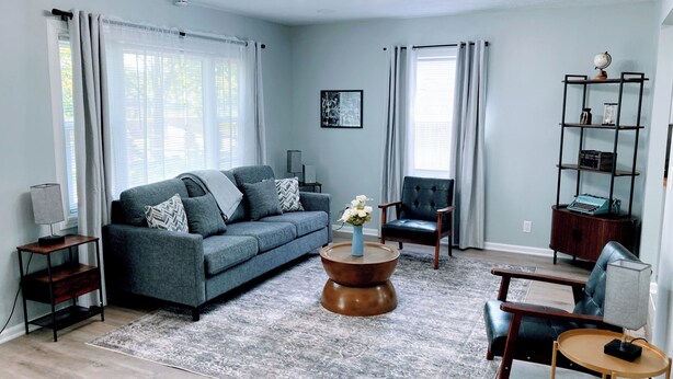 A living room with a sofa, armchair, coffee table, and a bookshelf. - Indy-Themed Classic: Ode to Hoosier Spirit (Indianapolis)
