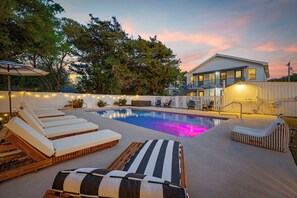 Una piscina con lettini, un solarium e una casa sullo sfondo.