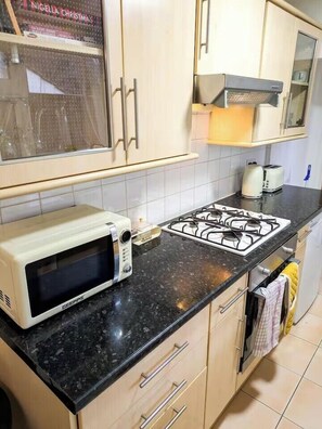 A kitchen with a microwave, toaster, gas stove, and cabinets. - Sleeps 6 - Parking - Garden - Wifi - Bbq (Gravesend)