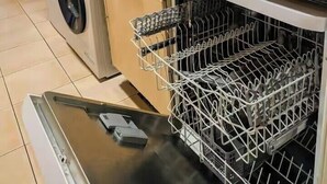 Keittiössä on pesukone, pesuallas, astiateline ja ikkunalaudalla kasveja.