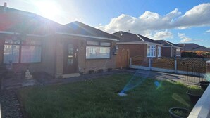 A residential property with a well-maintained lawn, a garage, and a brick exterior.