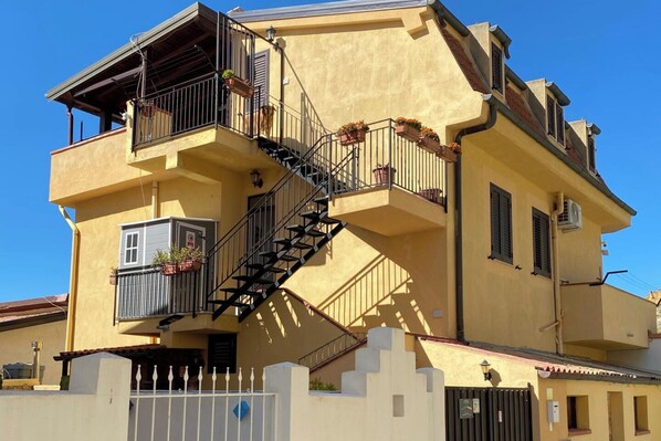 A multi-story building with a staircase, balconies, and potted plants.