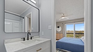 Ein Schlafzimmer mit Bett, Deckenventilator und Blick ins Freie.