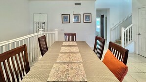 Un espace repas comprenant une longue table, des chaises et un escalier.