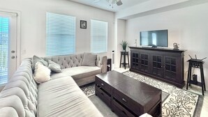 Un salon comprenant un canapé, une table basse, un téléviseur, un meuble et un ventilateur de plafond.