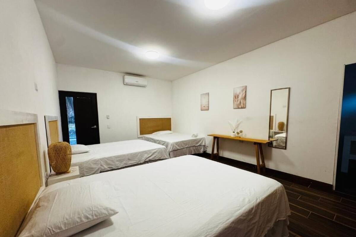A hotel room with two single beds, a small table, a mirror, and a door.