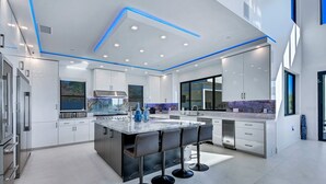 A modern kitchen with a central island, bar stools, and built-in appliances. - Villa Fabulosa - Luxurious Bedrooms, Pool, Pickleball, Mini Golf, Game Room, 360 degree view and more (Temecula)