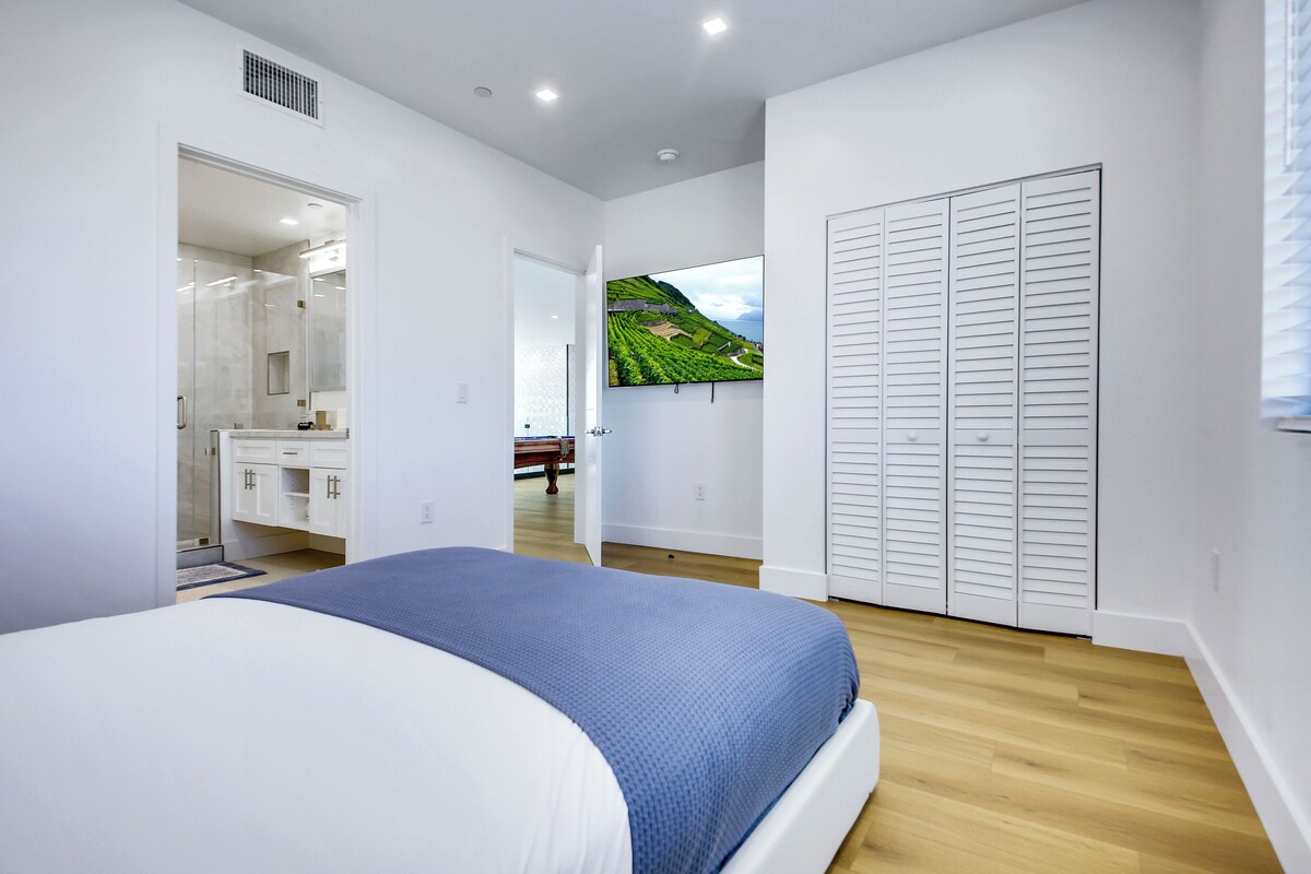 Ein Schlafzimmer mit Bett, begehbarem Kleiderschrank, Badezimmer und Blick auf einen Weinberg.