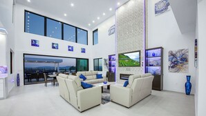 A spacious living area with a high ceiling, large windows, and a fireplace. - Villa Fabulosa - Luxurious Bedrooms, Pool, Pickleball, Mini Golf, Game Room, 360 degree view and more (Temecula)