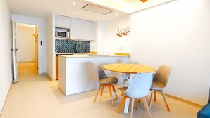 Una cocina moderna con microondas, salpicadero tipo espiga y una pequeña isla con fregadero. Hay un comedor con una mesa redonda y cuatro sillas.