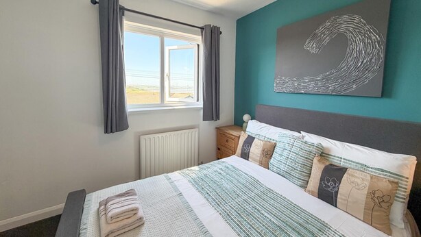 Una camera da letto con un letto, una finestra, un termosifone, un comodino e un quadro appeso al muro.