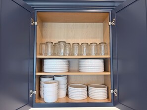 A cabinet with glass jars and stacked plates.